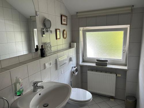 a bathroom with a sink and a toilet and a window at Gemütliche Wohnung in Baldham bei München in Vaterstetten