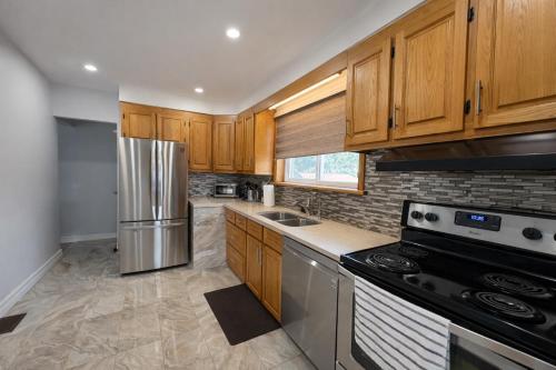 a kitchen with wooden cabinets and a stainless steel refrigerator at Newly Renovated 3BR North York Bungalow with Backyard Patio & Volleyball Set! Close to Rogers Stadium, TTC Subway Access, Perfect for Family Travel, Group Trips & Work Stays! in Toronto