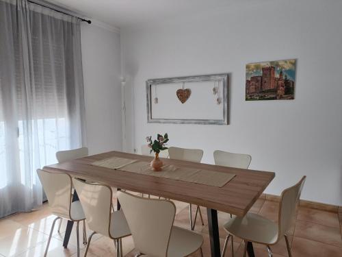 a dining room with a wooden table and white chairs at Aracena Centro by Aracena Rural Exp in Aracena