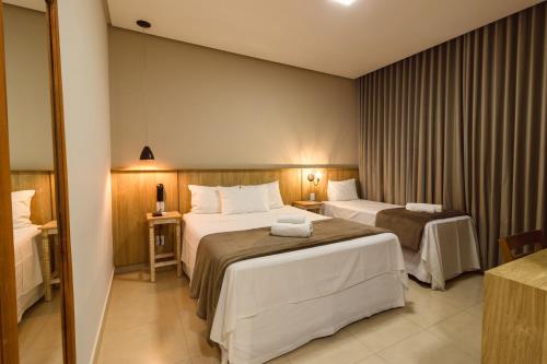 a hotel room with two beds and a mirror at Pousada Viver Capitólio in Capitólio