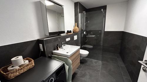 a black and white bathroom with a sink and a shower at Ferienwohnung Wiesenweg - Aktiv im Allgäu in Seeg