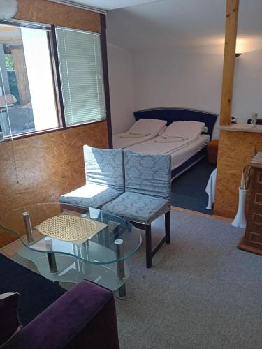 un soggiorno con un letto e un tavolo di vetro di Ravne Apartman a Visoko