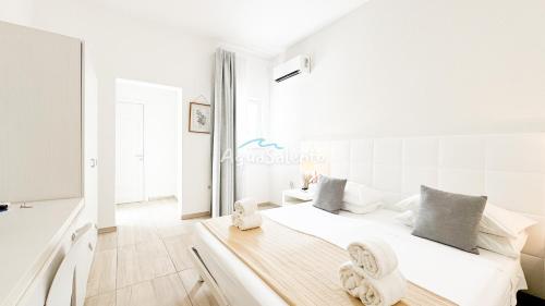 a white bedroom with a bed with towels on it at AQUARAMA Rooms & Apartments in Torre Squillace