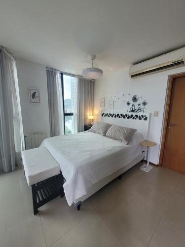 a bedroom with a large white bed and a window at Apartamento Ejecutivo Premium Riviera Tower in Villa Carlos Paz