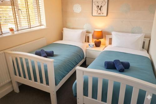 two twin beds in a room with a window at Spacious 5BR Home with Garden, Games & Parking Near Heathrow Windsor in Slough