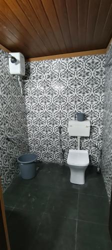 a bathroom with a toilet and a wall at Agastya Beach House in Ullāl