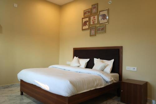 a bedroom with a bed with white sheets and pictures on the wall at Monkey River Resort Madla in Rājgarh