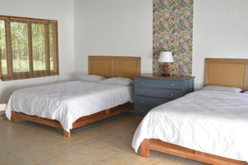 a bedroom with two beds and a dresser and window at Hooked on Panama Lodge in Limones