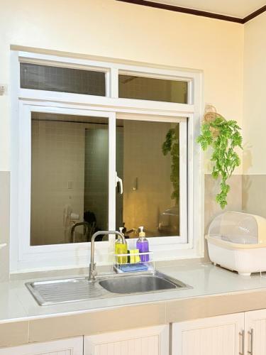 a kitchen sink with a window above it at Casita del Mabini - Homestay in Mabini