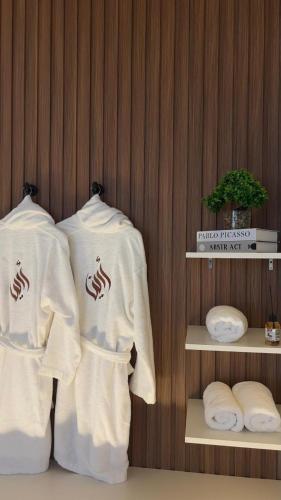 two white shirts are hanging on a wall at Areenachalet in Ibrā
