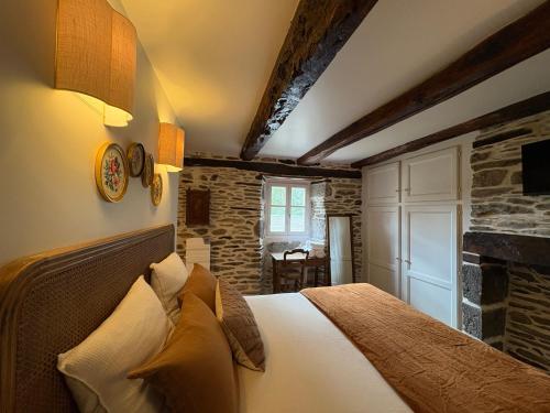 a bedroom with a bed and a stone wall at La Roulière en Aubrac in Montpeyroux