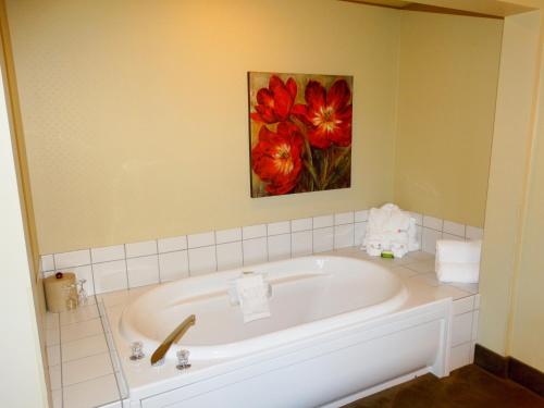 a bathroom with a bath tub with a painting on the wall at Amsterdam Inn & Suites Sussex in Sussex