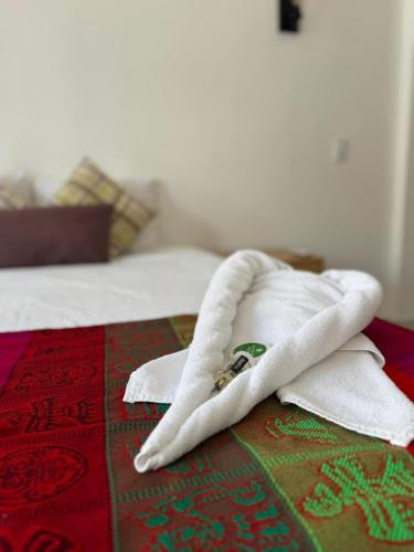 a white towel on top of a bed at Calma Chicha Rooms in Playa del Carmen