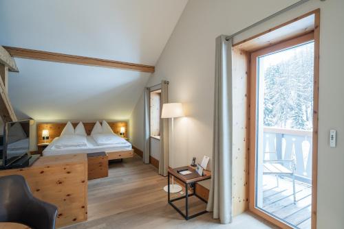 a bedroom with a bed and a large window at The Alpina Mountain Resort in Tschiertschen