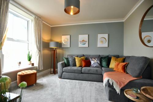 a living room with a gray couch with colorful pillows at Island View in Benllech
