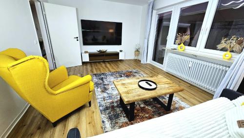a living room with a yellow chair and a table at Ioana Homes Ferienwohnung in Abstatt