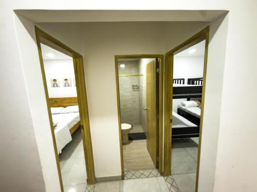 a bathroom with two mirrors and a room with two beds at Coral del mar in Tolú