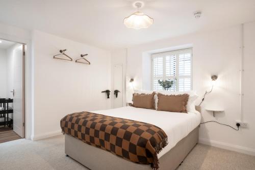 a white bedroom with a bed with a checkered blanket on it at Apartment ONE in Sherborne