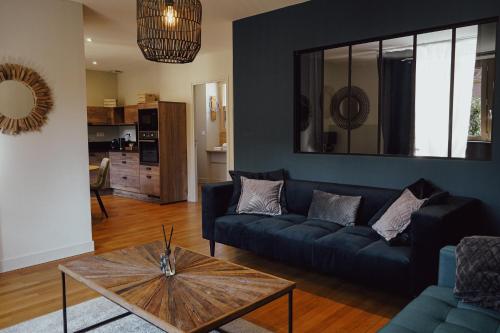 a living room with a blue couch and a table at Les Suites Gueguen in Chablis