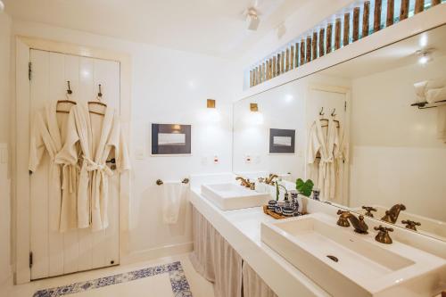 a white bathroom with two sinks and a mirror at TW Guaimbê Exclusive Suítes in Ilhabela