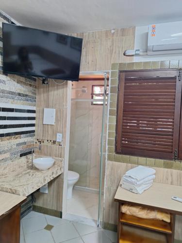 a bathroom with a sink and a toilet and a television at Casa com ar condicionado in Lauro de Freitas