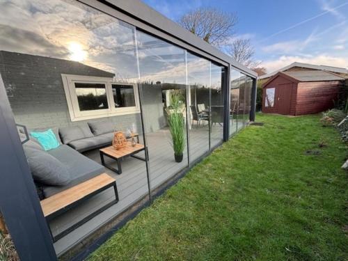 a screened in backyard with a couch and a table at Strandnahes Ferienhaus NR 2 mit Wintergarten grosser uneinsehbarer Garten in Sint Maartensvlotbrug