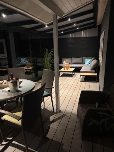 a patio with a couch and a table and chairs at Strandnahes Ferienhaus NR 2 mit Wintergarten grosser uneinsehbarer Garten in Sint Maartensvlotbrug