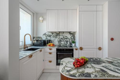a kitchen with white cabinets and a bowl of fruit on a counter at Lumina I Premium 3BR Apartment with Balcony I City View in Warsaw