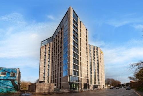 a tall building with glass windows on a street at For Students Only Stylish Studios in Glasgow in Glasgow