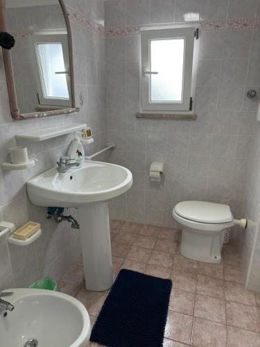 a bathroom with a sink and a toilet and a mirror at Ponzamania Terrazza sul tramonto in Ponza