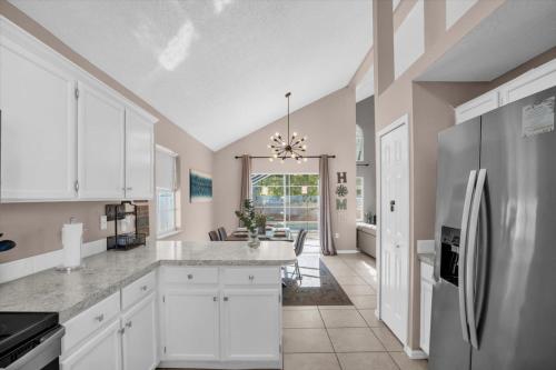 a kitchen with white cabinets and a refrigerator at Elegant Villa Pool Fun Game Room Near Disney in Kissimmee