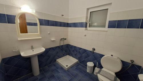 a blue and white bathroom with a toilet and a sink at Ninareti Studios in Agia Paraskevi