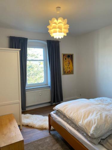 a bedroom with a bed and a window and a chandelier at Stadtgarten in Meißen