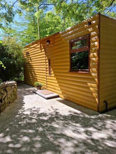 a small wooden cabin with a window in a yard at The Swallow's Return LogCabin, Carlingford, A91D954 in Carlingford