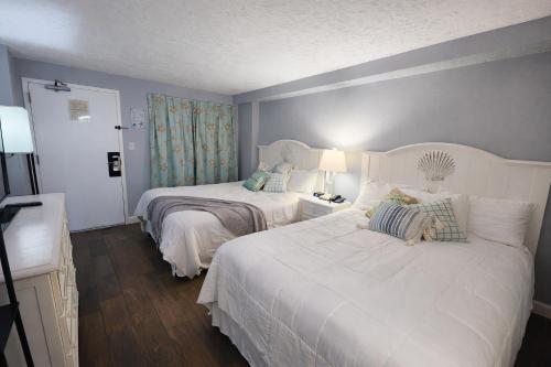 a bedroom with two beds with white sheets and blue walls at Heated Pools, Heated lazy river, 3 hot tubs-Privately owned Oceanfront renovated condo on 12th floor in Myrtle Beach