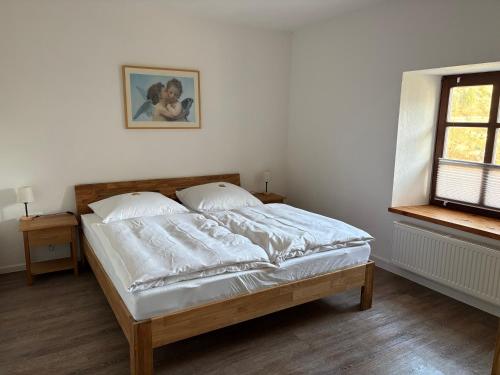 a bedroom with a bed with white sheets and a window at Felsenhäuschen in Monschau
