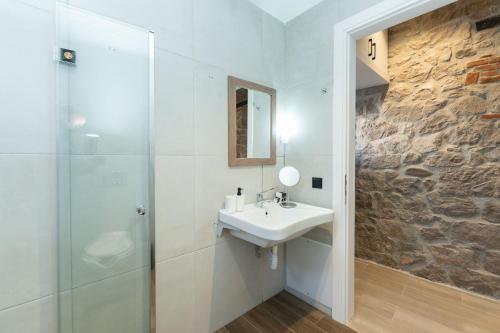 a white bathroom with a sink and a shower at MONOPATI HOUSE in Mouzaki