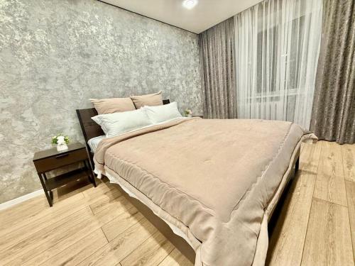 a bedroom with a large bed and a side table at Two-room apartment in Astana