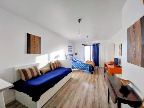 a living room with a blue couch and a desk at Madeira Native Motion Guest House in Fajã da Ovelha
