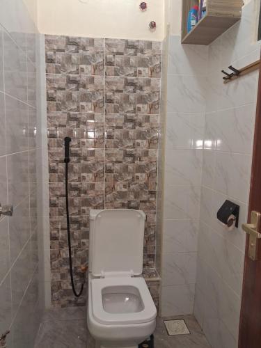 a bathroom with a toilet and a stone wall at Shalom - Stays in Voi