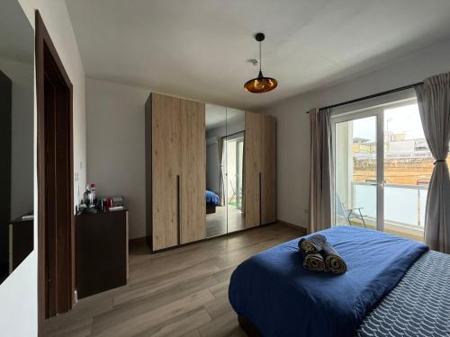 a bedroom with a blue bed and a large mirror at Airport Accommodation Bedroom with Bathroom, balcony, aircondition, self checkIn, 24 hours check-in after 3pm in Mqabba
