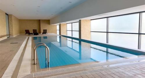 a large swimming pool in a building with windows at Luxury Tróia T1 Pool, Sauna Parking in Troia