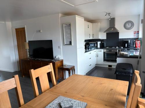 a kitchen with a wooden table and a dining room at Cosy Annexe With Peaceful Surroundings in Upwell