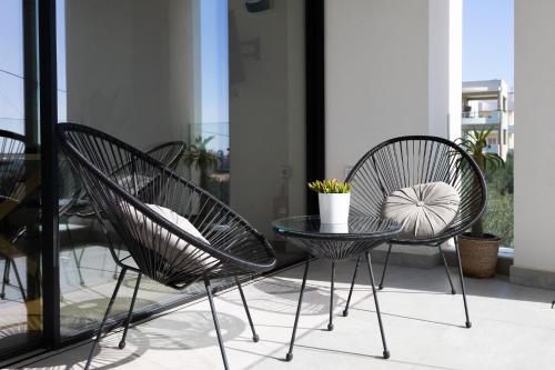 three chairs and a glass table on a balcony at The L Smart Suite - Premium & Minimal in Ierapetra