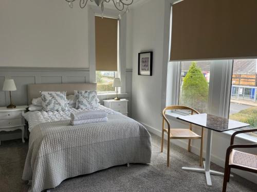 a bedroom with a bed and a table and a window at Giffnock Rooms in Giffnock