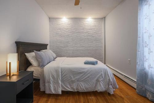 a bedroom with a white bed and a brick wall at Cozy Room in the City of Worcester in Worcester
