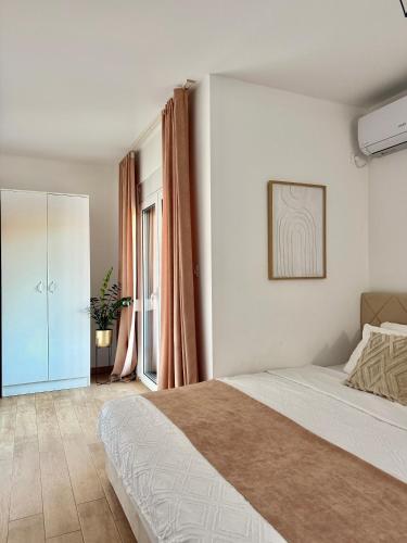 a white bedroom with a bed and a window at Danin apartmani in Bar
