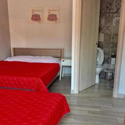a bedroom with two red beds and a bathroom at Soso studios & apartments in Stavros