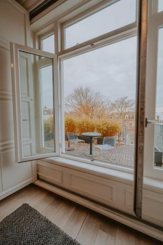 a room with a large window with a table and chairs at Boutique Hotels MANNA & Blue in Nijmegen