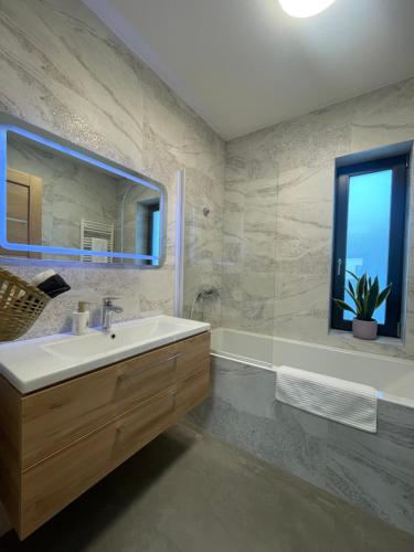 a bathroom with a sink and a mirror and a tub at Rolling Hills Holiday Haven in Odorheiu Secuiesc